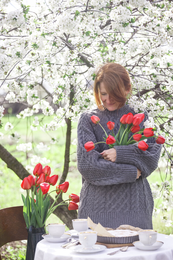 Een persoon die mediteert in een Nederlandse tuin met tulpen en windmolens op de achtergrond